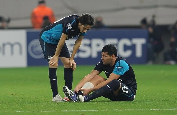 Andre Santos Holds Injured Ankle as Yossi Benayoun Looks On: Olympiacos vs. Arsenal, UEFA Champions League, 2011