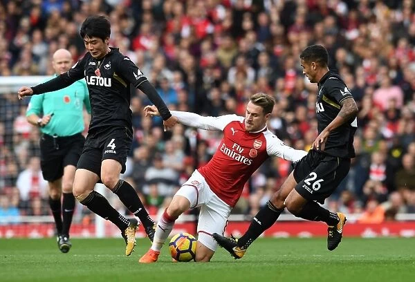 Arsenal's Aaron Ramsey Faces Off Against Ki Sung-Yeung and Kyle Naughton of Swansea during the 2017-18 Premier League Match