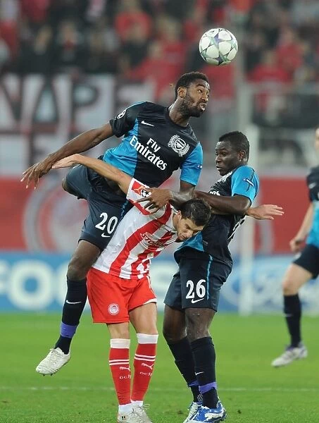 Arsenal's Johan Djourou Leaps Over Frimpong to Challenge Mirallas in Olympiacos Clash