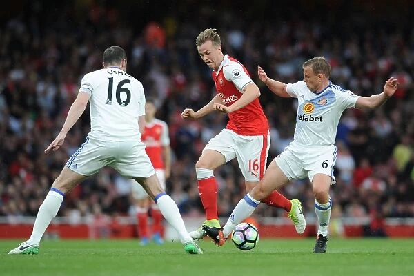 Arsenal's Rob Holding Clashes with Sunderland's John O'Shea and Lee Catermole during the Premier League Match