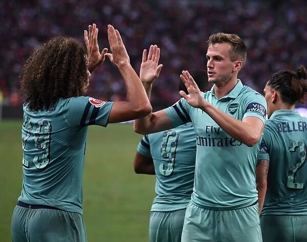 Arsenal's Unstoppable Moment: Holding and Guendouzi Celebrate Goal Against Paris Saint-Germain