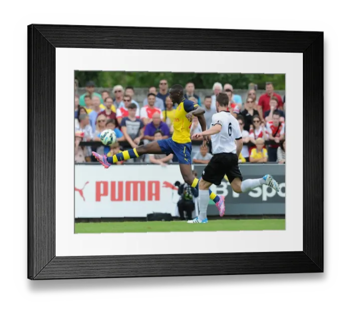 Framed Print : Yaya Sanogo (Arsenal) Callum Reynolds (Boreham Wood). Boreham Wood 0: 2 Arsenal. Pre Season Friendly