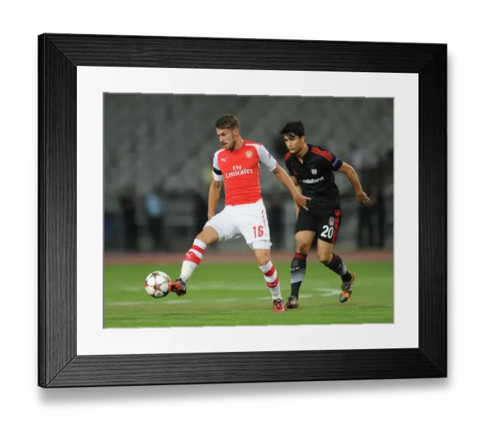 Framed Print : Aaron Ramsey Outmaneuvers Necip Uysal in Arsenal's UEFA Champions League Clash against Besiktas