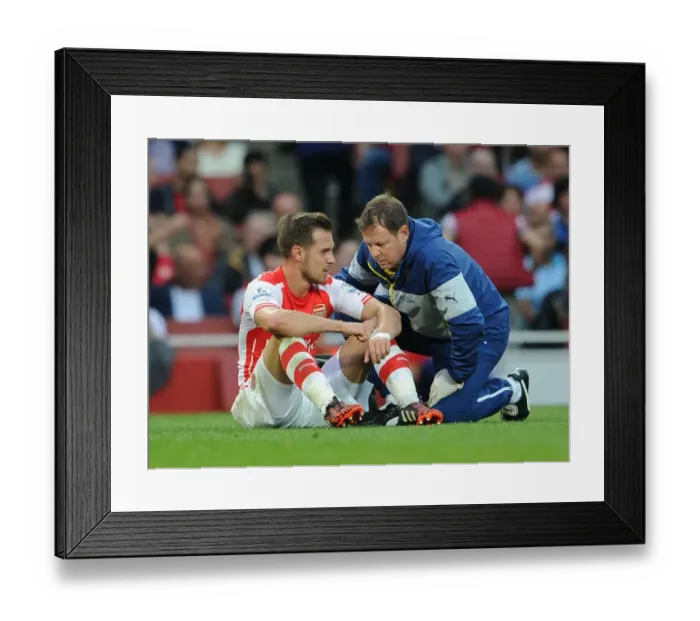 Framed Print : Arsenal's Aaron Ramsey Consults Physio Colin Lewin During Arsenal v Tottenham Clash