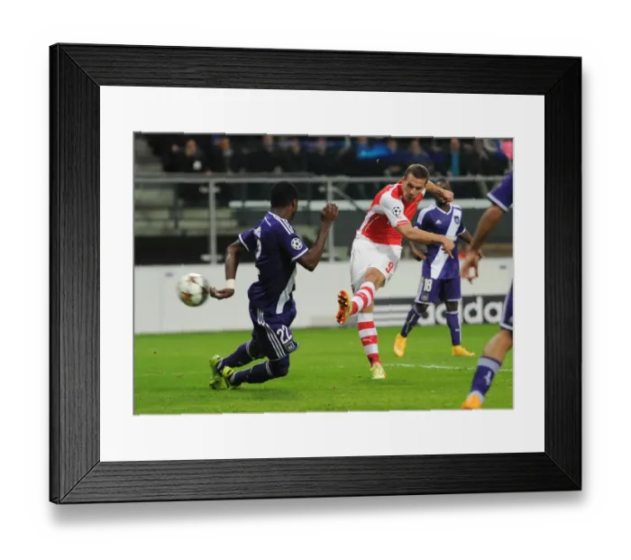 Framed Print : Lukas Podolski Scores Against Chancel Mbemba: Arsenal's Victory in the UEFA Champions League against RSC Anderlecht (2014)