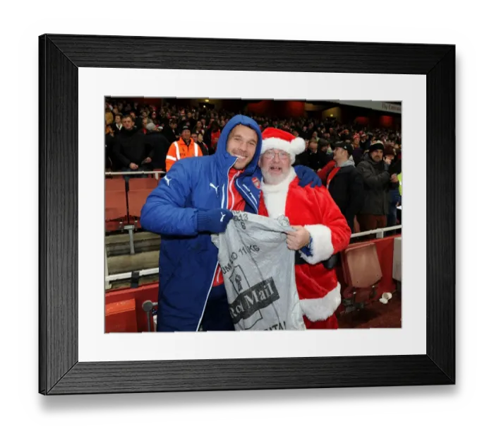 Framed Print : Arsenal's Festive Surprise: Lukas Podolski and the Arsenal Chef Dressed as Father Christmas Ahead of Arsenal v Newcastle United Match