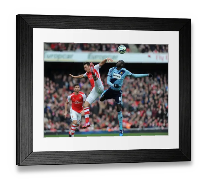 Framed Print : Arsenal vs. West Ham United: Intense Clash between Ozil and Kouyate in the Premier League Framed Print : Arsenal vs. West Ham United: Intense Clash between Ozil and Kouyate in the Premier League