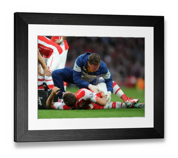 Framed Print : Arsenal's Olivier Giroud Receives Medical Attention from Physio Colin Lewin during Swansea City Match (2015)