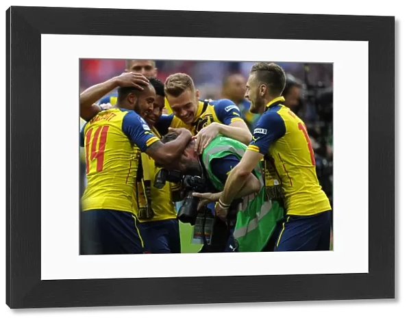 Arsenal photographer Stuart MacFarlane is grabbed by Aaron Ramsey and Theo Walcott after the match