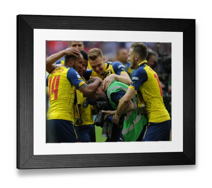 Framed Print : Arsenal photographer Stuart MacFarlane is grabbed by Aaron Ramsey and Theo Walcott after the match