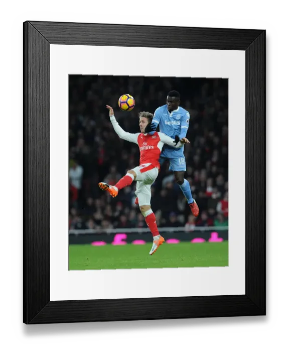 Framed Print : Monreal vs. Diouf: Heading Battle at Emirates Stadium - Arsenal v Stoke City, Premier League 2016-17