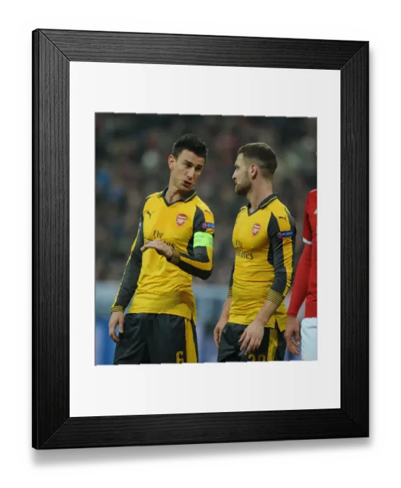 Framed Print : Arsenal's Koscielny and Mustafi Go Head-to-Head Against Bayern Munich in Champions League Clash