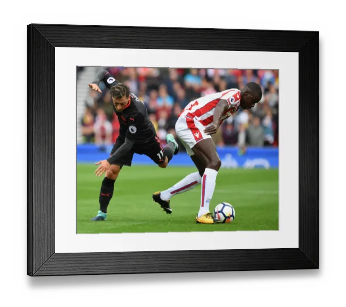 Framed Print : Mesut Ozil vs Kurt Zouma: Intense Battle in Stoke City vs Arsenal Premier League Clash