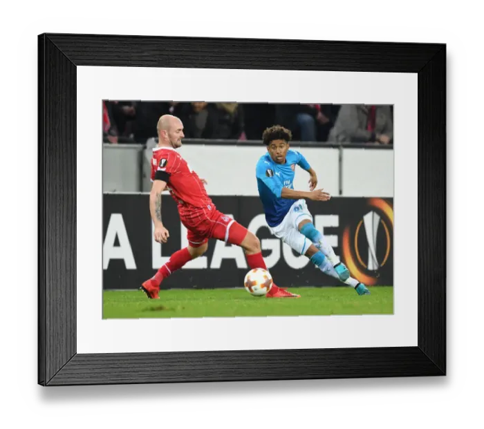Framed Print : Reiss Nelson vs. Konstantin Rausch: Battle in the Europa League between FC Koln and Arsenal FC