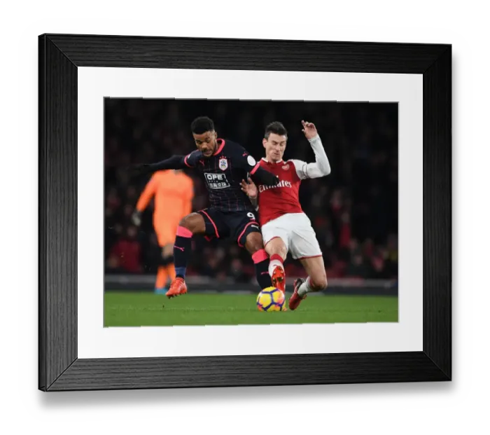 Framed Print : Arsenal's Koscielny Faces Off Against Huddersfield's Kachunga in Premier League Clash Framed Print : Arsenal's Koscielny Faces Off Against Huddersfield's Kachunga in Premier League Clash