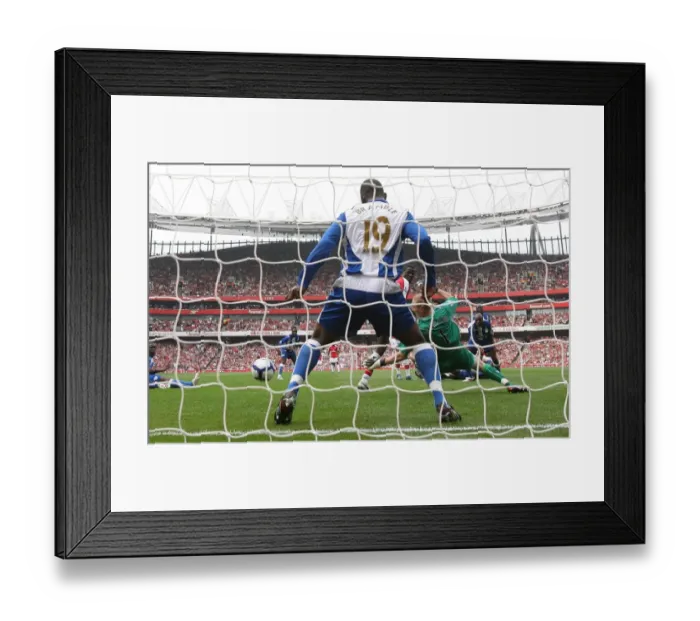 Framed Print : Emmanuel Eboue deflects the ball past Wigan goalkeeper Framed Print : Emmanuel Eboue deflects the ball past Wigan goalkeeper