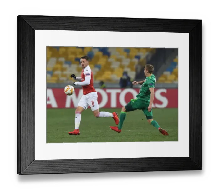 Framed Print : Aaron Ramsey vs. Igor Perduta: Intense Clash in Arsenal's UEFA Europa League Match against Vorskla Poltava Framed Print : Aaron Ramsey vs. Igor Perduta: Intense Clash in Arsenal's UEFA Europa League Match against Vorskla Poltava