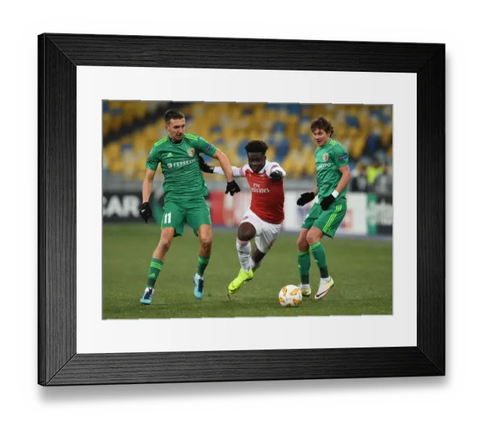 Framed Print : Arsenal's Bukayo Saka Faces Off Against Vorskla Poltava's Sharpar and Rebenok in UEFA Europa League Clash
