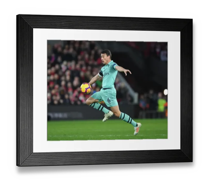 Framed Print : Arsenal's Koscielny Faces Off Against Liverpool in Premier League Clash