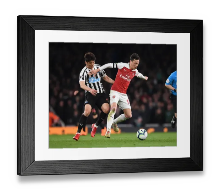 Framed Print : Arsenal's Mesut Ozil Clashes with Newcastle's Ki Sung-Yueng in Premier League Showdown