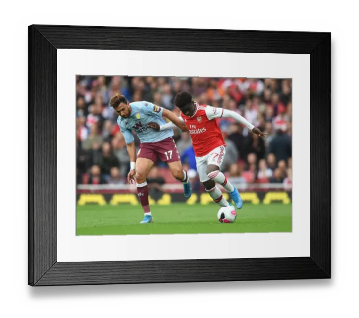 Framed Print : Arsenal's Bukayo Saka Clashes with Aston Villa's Trezeguet in Premier League Showdown