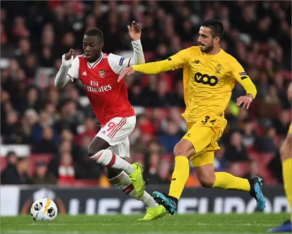Arsenal's Nicolas Pepe Outmaneuvers Standard Liege's Kostas Laifis in UEFA Europa League Clash