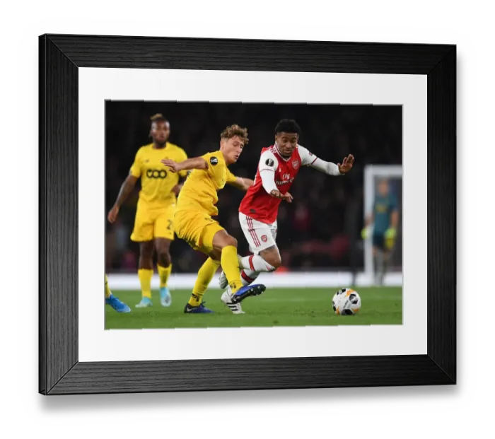 Framed Print : Arsenal's Reiss Nelson Clashes with Standard Liege's Mergim Vojvoda in Europa League Showdown