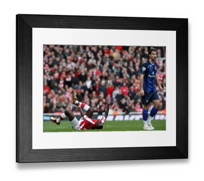Framed Print : Emmanuel Eboue (Arsenal) holds his ankle following a challenge from Lorik Cana