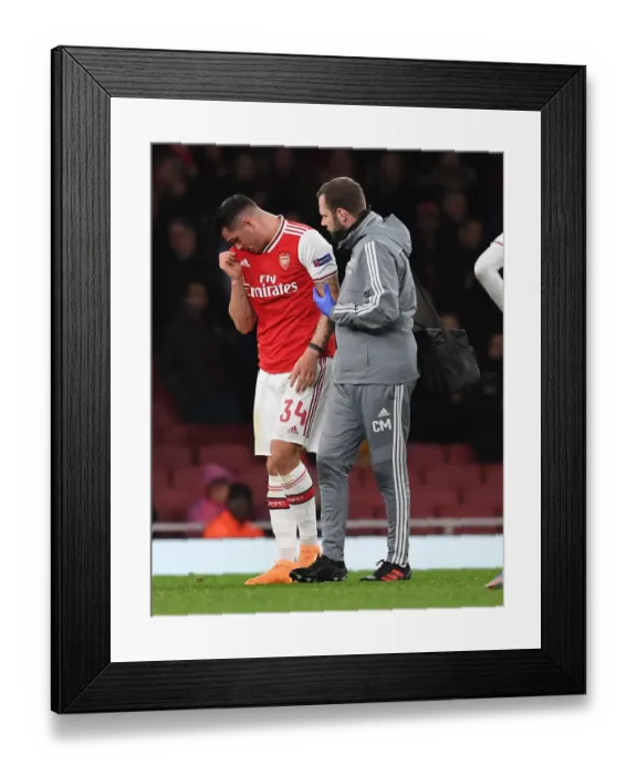 Framed Print : Arsenal's Granit Xhaka Receives Treatment from Physio during Arsenal v Eintracht Frankfurt UEFA Europa League Clash