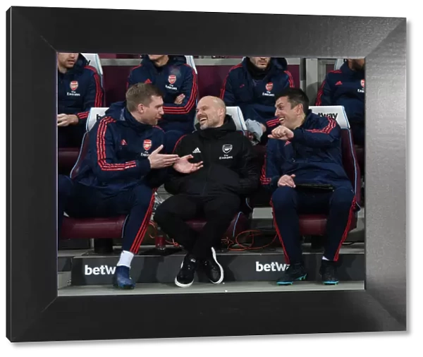 Arsenal Coaches Ljungberg, Mertesacker, and Bibbo Share a Lighthearted Moment on the Sidelines during Arsenal's Match against West Ham