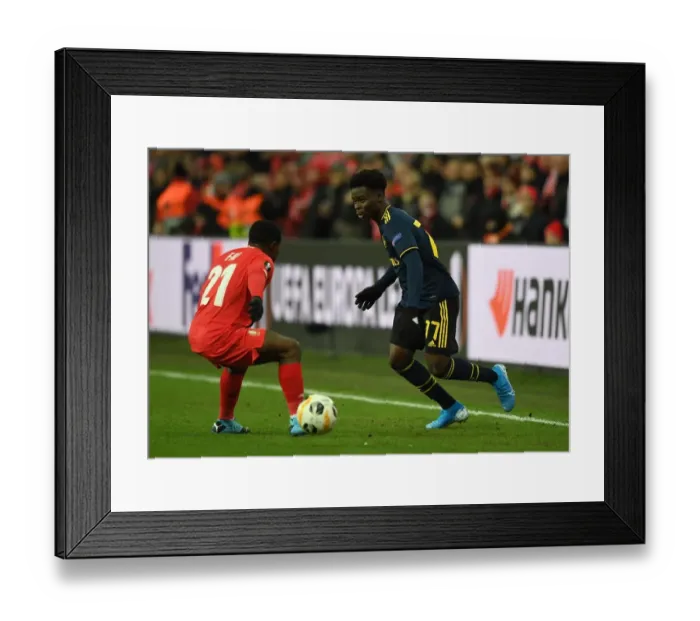 Framed Print : Bukayo Saka Faces Off Against Collins Fai in Arsenal's Europa League Clash with Standard Liege