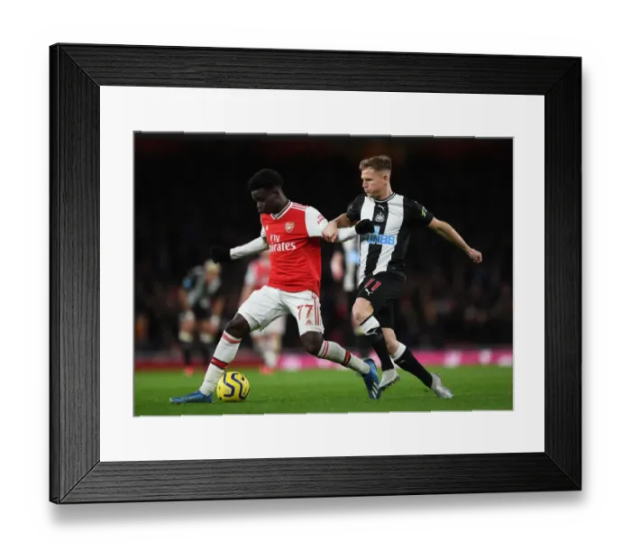 Framed Print : Arsenal's Bukayo Saka Clashes with Newcastle's Matt Ritchie in Premier League Showdown Framed Print : Arsenal's Bukayo Saka Clashes with Newcastle's Matt Ritchie in Premier League Showdown