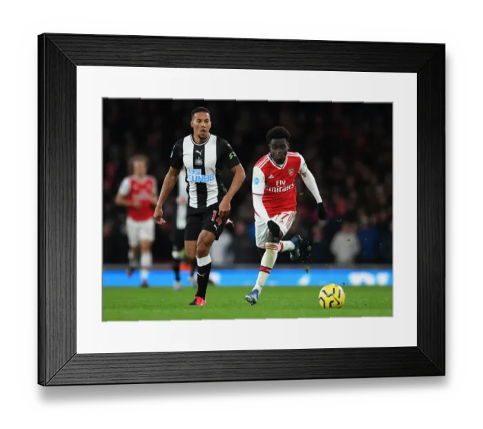 Framed Print : Arsenal's Bukayo Saka Clashes with Newcastle's Isaac Hayden in Premier League Showdown