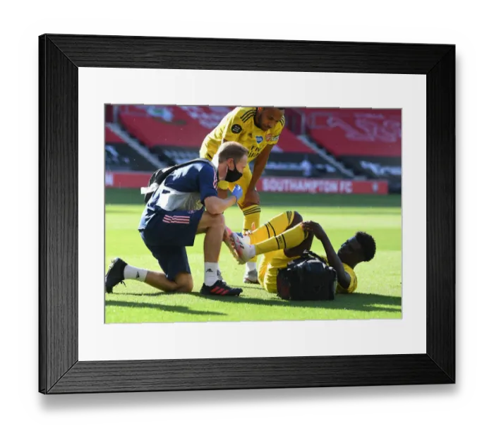 Framed Print : Arsenal's Bukayo Saka Receives Treatment from Physio during Southampton Clash (2019-20) Framed Print : Arsenal's Bukayo Saka Receives Treatment from Physio during Southampton Clash (2019-20)