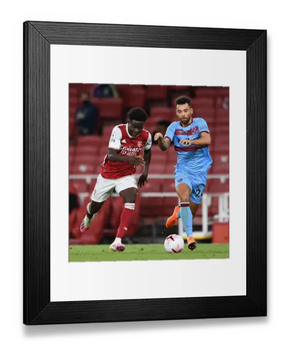 Framed Print : Arsenal's Bukayo Saka Faces Off Against West Ham's Ryan Fredericks in Premier League Clash