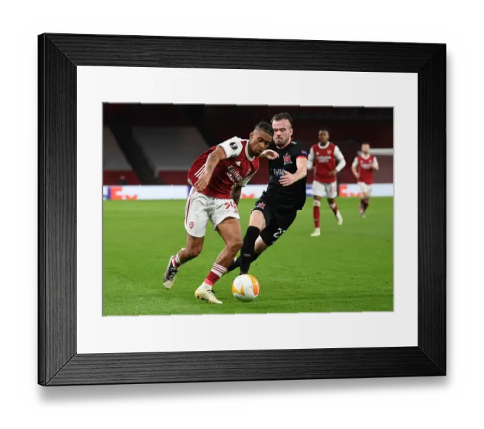 Framed Print : Arsenal's Reiss Nelson Goes Head-to-Head with Dundalk's Cameron Dummigan in Empty Emirates Stadium - UEFA Europa League 2020-21