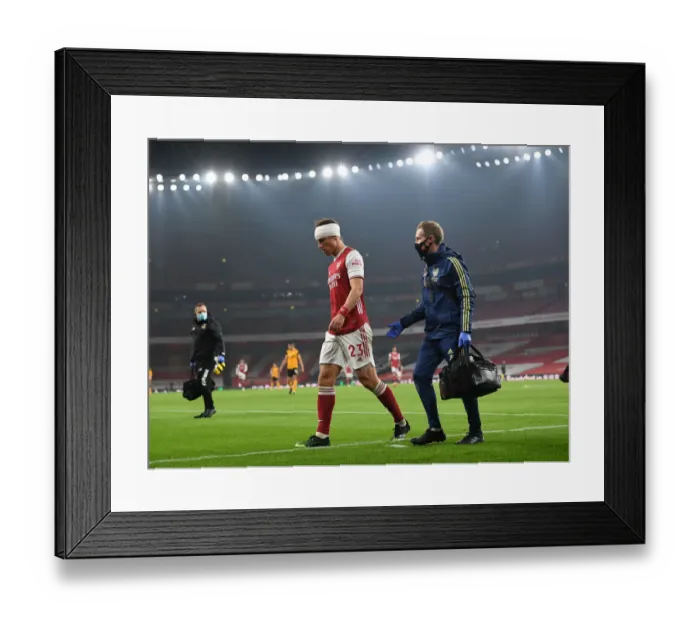 Framed Print : Arsenal's Empty Emirates: David Luiz Receives Treatment Alone Amidst Quiet Stadium Crowds (2020-21 Premier League: Arsenal vs. Wolverhampton Wanderers)