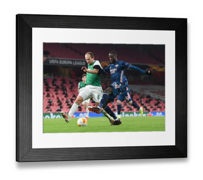 Framed Print : Arsenal's Nicolas Pepe Goes Head-to-Head with Rapid Wien's Mario Sonnleitner in Empty Emirates Stadium - UEFA Europa League 2020-21