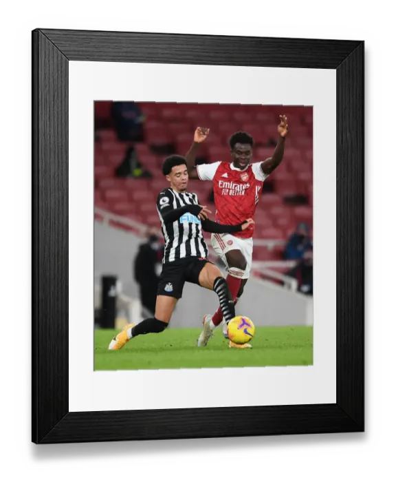 Framed Print : Arsenal vs Newcastle United: Bukayo Saka Tangles with Jamal Lewis in Empty Emirates Stadium