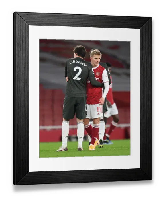 Framed Print : Arsenal's Odegaard Embraces Lindelof Amid Empty Emirates Stadium - Arsenal vs Manchester United, 2021