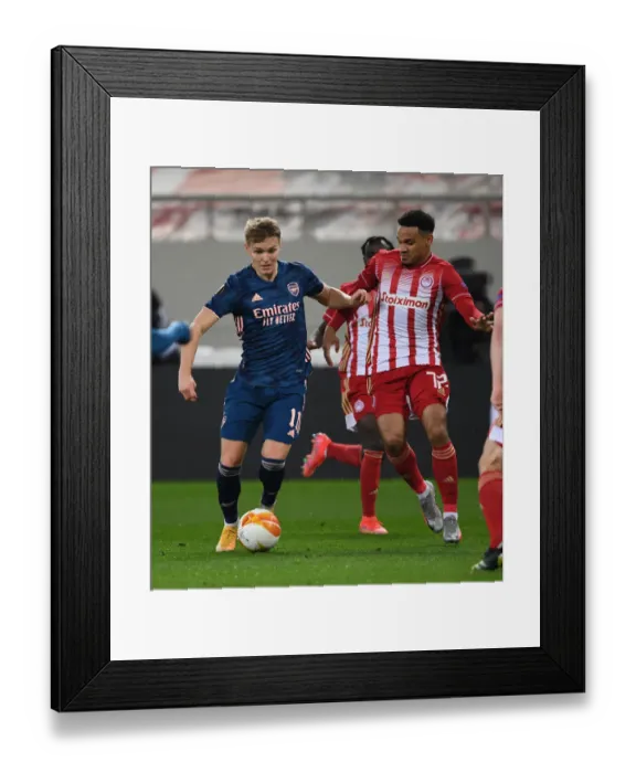 Framed Print : Arsenal's Martin Odegaard Clashes with Olympiacos Kenny Lala in UEFA Europa League Match Amidst Empty Stands Framed Print : Arsenal's Martin Odegaard Clashes with Olympiacos Kenny Lala in UEFA Europa League Match Amidst Empty Stands