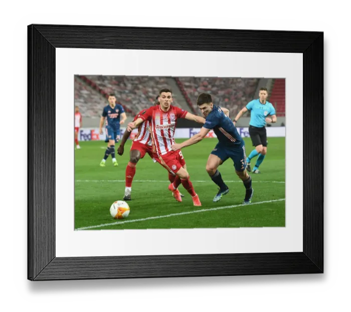 Framed Print : Arsenal's Kieran Tierney Goes Head-to-Head with Olympiacos Lazar Randjelovic in Empty Europa League Stadium