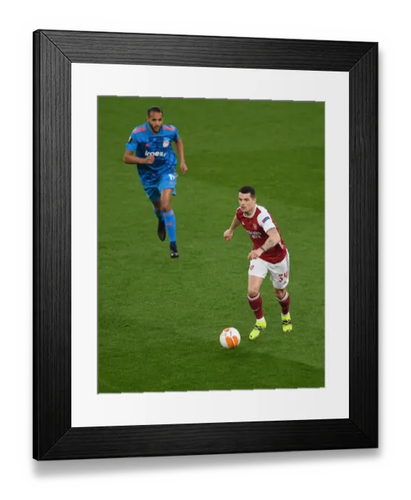 Framed Print : Arsenal's Granit Xhaka in UEFA Europa League: A Lone Warrior Amidst Empty Seats vs. Olympiacos