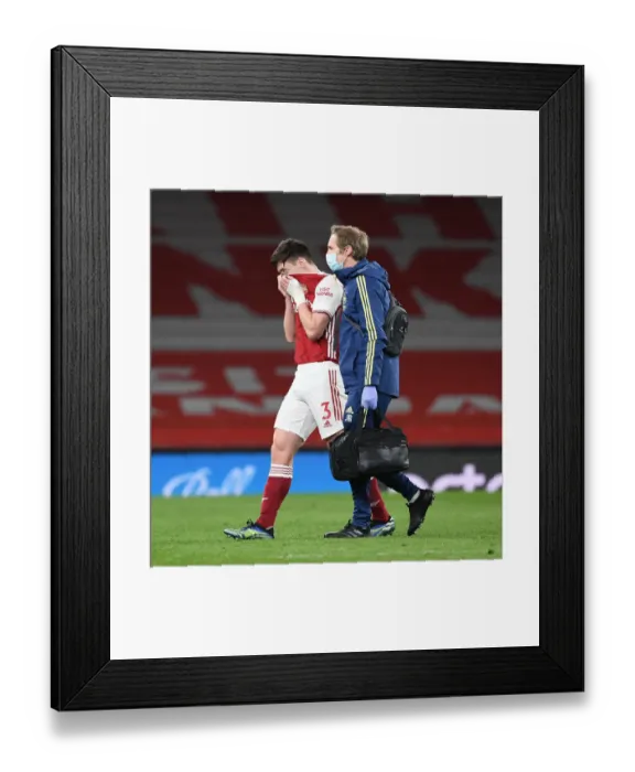 Framed Print : Arsenal's Kieran Tierney Exits with Injury as Emirates Stadium Remains Empty for Arsenal v Liverpool (2021)