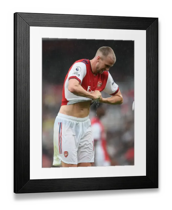 Framed Print : Arsenal's Rob Holding Rings Out Drenched Shirt in Heavy Premier League Rainfall (2021-22)