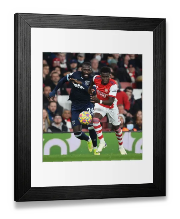 Framed Print : Saka Slices Through Masuaku: Arsenal's Star Outmaneuvers West Ham Defender in Premier League Clash Framed Print : Saka Slices Through Masuaku: Arsenal's Star Outmaneuvers West Ham Defender in Premier League Clash