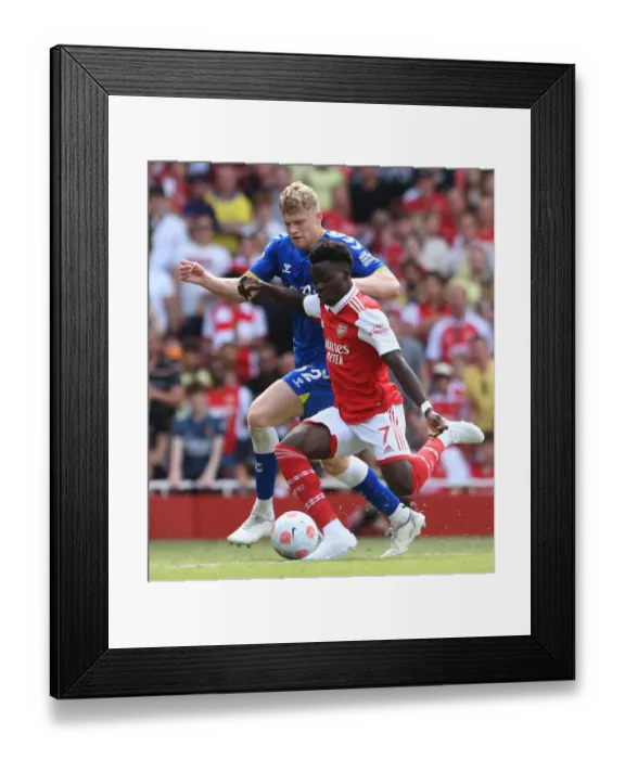 Framed Print : Arsenal's Bukayo Saka Faces Off Against Everton's Jarrad Branthwaite in Premier League Showdown