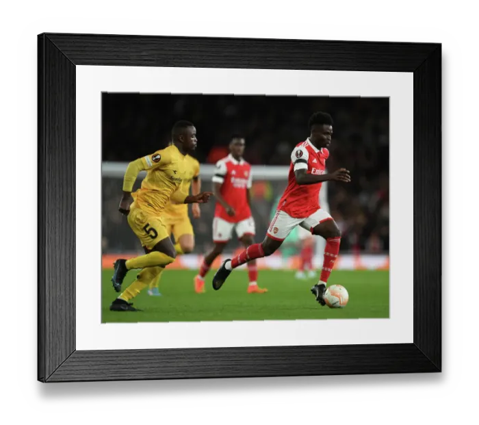 Framed Print : Arsenal's Bukayo Saka Goes Head-to-Head with Brice Wenbangomo in Europa League Showdown