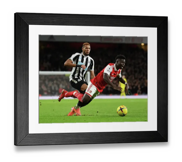 Framed Print : Arsenal's Bukayo Saka Clashes with Newcastle's Joelinton in Premier League Showdown