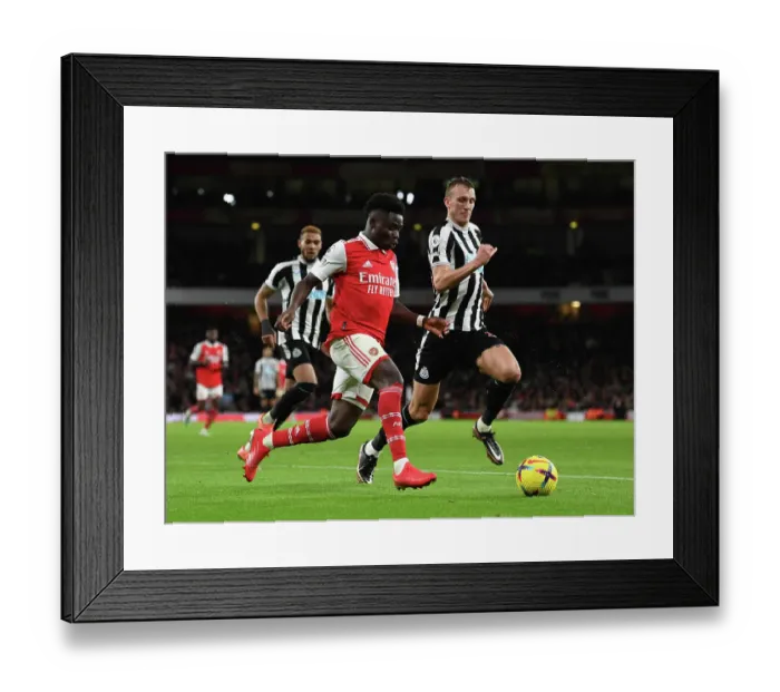 Framed Print : Arsenal's Bukayo Saka Clashes with Newcastle's Dan Burn in Premier League Showdown